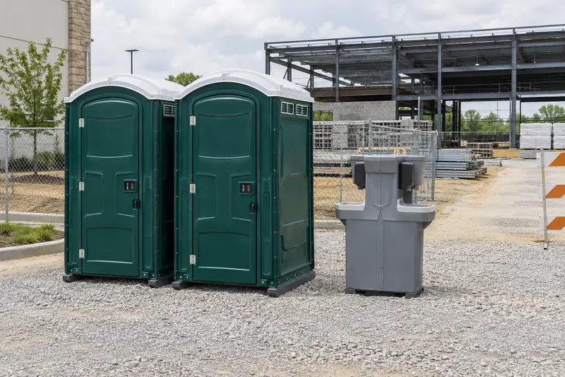 Portable toilets and a handwashing station beside a building worksite